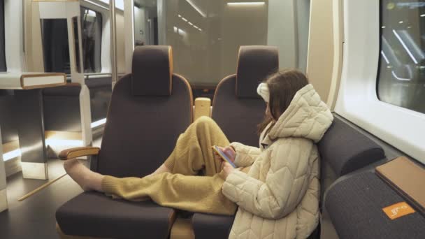 10代の少女は 高速急行列車の地下を旅し スマートフォンのソーシャルメディアをスクロールし 窓のそばに座っている 通勤電車の長い旅 — ストック動画