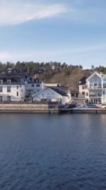 Baharın başlarında Norveç fiyordunun sahil şeridinde sürüş plakası. Drammenfjord sahili boyunca Panorama. Feribottan çekiyoruz. Dikey video