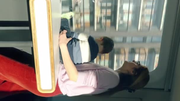 一位年轻的妇女和她的孩子乘坐高速快车 欣赏窗外美丽的风景 探索新的地方 垂直录像 — 图库视频影像