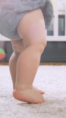 Bebek evde ilk adımları atarak yürümeyi öğreniyor. Oturma odasında yerde yürüyen küçük ayaklar