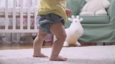 Bebek evde ilk adımları atarak yürümeyi öğreniyor. Oturma odasında yerde yürüyen küçük ayaklar