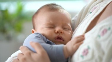 Kollarında uyuyan bir bebeği tutan mutlu bir anne. Sevgi dolu bir anne yeni doğmuş bebeğini evde taşır. Annelik, Ebeveynlik ve Annelik. Güzel Mutlu Aile. Yakın plan.