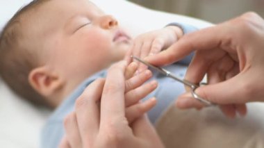 Önemseyen anne minik bebek parmaklarıyla bebek tırnağı kesiyor. Annelik, Ebeveynlik ve Annelik. Sağlıklı Mutlu Aile. Yakın çekim, eğim kaydırma lensi