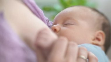 Genç bir anne yeni doğmuş bir bebeği hafif bir yatak odasında emziriyor. Annem bebeğini kucağına alıp sarılıyor. Annelik, Ebeveynlik ve Annelik. Güzel Mutlu Aile. Yakın çekim, eğim kaydırma lensi