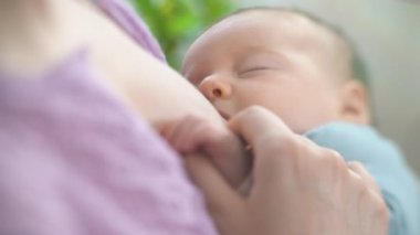 Genç bir anne yeni doğmuş bir bebeği hafif bir yatak odasında emziriyor. Annem bebeğini kucağına alıp sarılıyor. Annelik, Ebeveynlik ve Annelik. Güzel Mutlu Aile. Yakın çekim, eğim kaydırma lensi