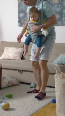 Baba oturma odasını temizliyor. Bebek bebekle birlikte bir sürü dağınık oyuncak topluyor..