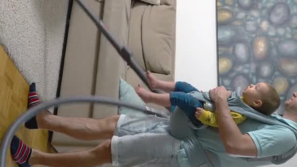 父真空クリーニングアパートの床とともに彼の幼児赤ちゃんで持ち運びスリング — ストック動画