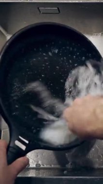 Mutfaktaki lavaboda bulaşık yıkayan erkeklerin üst görüntüsü. Dikey video