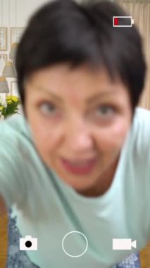 Olgun bir kadın evdeki sosyal medya hesabı için son moda dans hareketlerini kaydediyor. 50-60 yaşlarında bir kadın akıllı telefondan kısa video çekiyor. Sosyal medyayı, hikayeleri ve moda dansını kavrayın. Sıralama