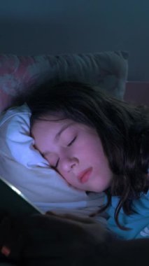 Genç kız gece yatakta yatarken akıllı telefon kullanıyor, sosyal medyayı karıştırıyor ve mesajlaşıyor. Sağlıklı uyku değil. Uykusuzluk ve yatmadan önce akıllı telefonun verdiği zarar. Sosyal ağlara bağımlılık