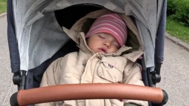 Küçük oğlan banliyöde yürürken bebek arabasının beşiğinde uyuyor. Geniş açı POV görüntüsü.