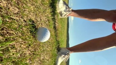 Golf oynayan olgun bir kadın. Kadın golfçü golf vuruşu yapıyor. Yeşil tepeleri ve mavi gökyüzü olan güneşli güzel bir manzara..