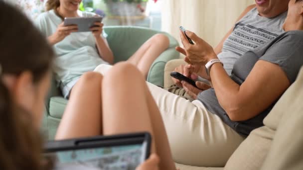 快乐的大家庭在家里一起玩网络游戏 不同年龄段的人坐在沙发上玩乐 祖父母和小女孩在客厅里用移动设备放松 — 图库视频影像