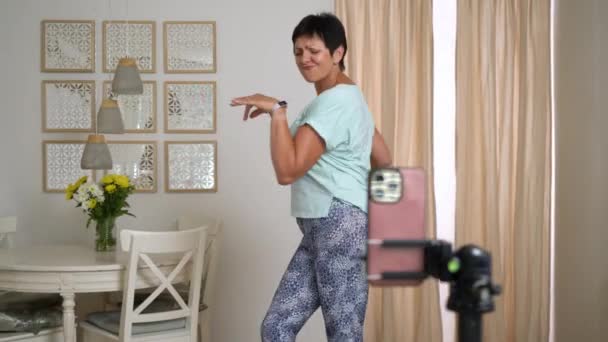 在家里记录流行舞步的成熟女性在社交媒体上的表现 60岁的妇女在智能手机上拍摄短片 概念社交媒体 故事和流行舞蹈 — 图库视频影像
