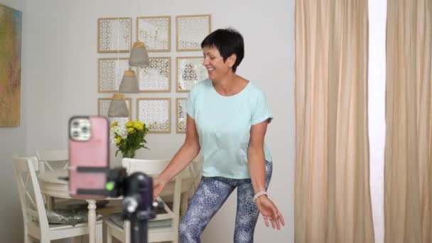 自宅でソーシャルメディアのアカウントのための流行のダンスの動きを記録熟女 女性50 60歳スマートフォンでショートビデオを撮影 ソーシャルメディア ストーリー 流行のダンスをコンセプトに — ストック動画
