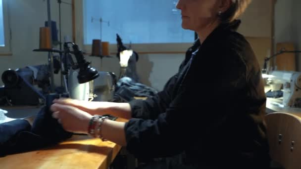 一位女裁缝在一家修理旧斜纹棉布衣服的车间里用老式真机缝制旧牛仔裤 小型家族企业 裁剪和修理服装 手工制作 — 图库视频影像