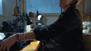 Helsinki, Finlandiya - 9 Kasım 2022: Eski kot pantolonları eski kot pantolonlara bağlayan kadın terzi eski kot pantolon tamir atölyesinde özel 43200 G.