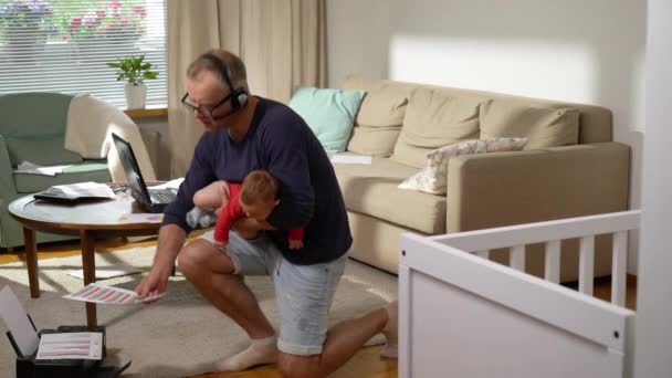 中年の父親と赤ちゃんが家で働いています 新生児のフリーランス シングル パパがビデオ通話をして自宅で文書を書く リモートジョブ マルチタスク 父親休暇 — ストック動画
