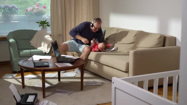 中年父亲带着孩子在家里干活 想让哭哭啼啼的孩子平静下来 一个带着新生儿的自由单身父亲打一个视频电话 在家里处理文件 远程工作 — 图库视频影像