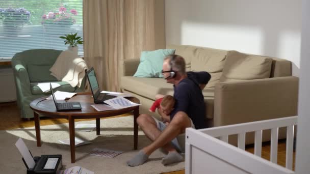有孩子在家里工作的中年父亲 一个带着新生儿的自由单身父亲打一个视频电话 在家里处理文件 远程工作 多重任务 陪产假和家庭假 — 图库视频影像