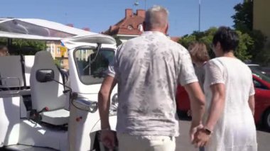 Bir grup turist Tuk-tuk elektrikli arabasıyla şehir merkezinden geçiyor. Gezginler eski kasabada çevre dostu bir araçla gezintiye çıkıyorlar.