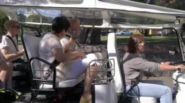 Bir grup turist Tuk-tuk elektrikli arabasıyla şehir merkezinden geçiyor. Gezginler eski kasabada çevre dostu bir araçla gezintiye çıkıyorlar.