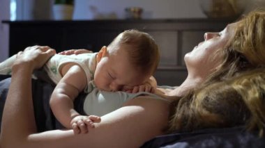 Yorgun bir anne, küçük oğluyla yatak odasında göğsünde yatıyor. Aile bağı. Annelik