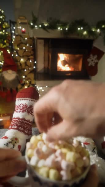 カップルは暖かい暖炉でマシュマロとココアを楽しんで クリスマスの装飾や装飾の背景とウールソックスで足を温めます コージーウィンター クリスマス そして — ストック動画