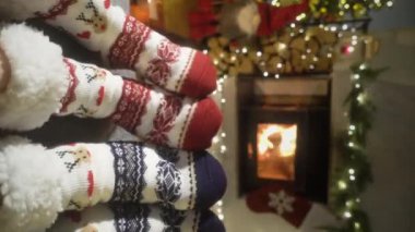 Sıcak şöminenin yanında eğlenen ve Noel süsleri, Noel ağacı ve dekorasyon arka planında yün çoraplarla ayaklarını ısıtan çift. Sıcak Kış, Noel ve Aile.