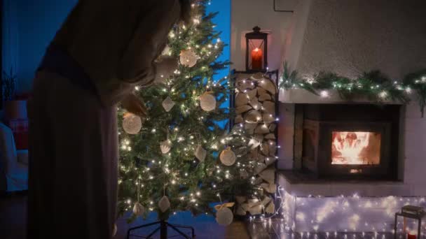 クリスマスツリーを飾る女性 タイムラプス 装飾された暖炉 クリスマスツリー ギフト付きの居心地の良い客室 — ストック動画