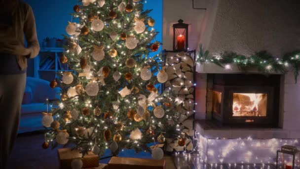 Μια Γυναίκα Που Στολίζει Ένα Χριστουγεννιάτικο Δέντρο Άνετο Δωμάτιο Διακοσμημένο — Αρχείο Βίντεο