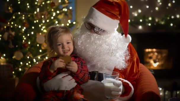 Ένα Μικρό Αγόρι Πιτζάμες Και Άγιος Βασίλης Τρώνε Χριστουγεννιάτικα Μπισκότα — Αρχείο Βίντεο