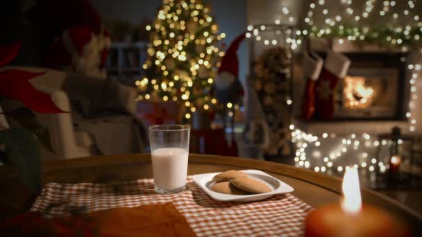 圣诞前夕 圣诞老人带着礼物 吃着生姜饼干 喝着牛奶 来到装饰了壁炉和圣诞树的客厅里 — 图库视频影像