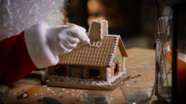 Noel Baba, evinde bir şömine ve Noel ağacıyla zencefilli kurabiye evi dekore ediyor.