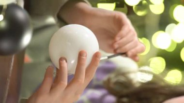 Noel arifesinde Noel süsleri çizen bir kız kutlamaya hazırlanıyor ve Noel ağacını süslüyor.