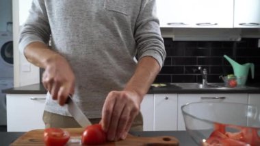 Genç adam mutfakta sebze salatası hazırlıyor. Mutlu adam sağlıklı yemek yapıyor..