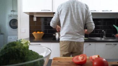 Genç adam mutfakta sebze salatası hazırlıyor. Mutlu adam sağlıklı yemek yapıyor..