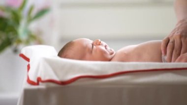 Genç anne bez değiştirip bebekle oynuyor. Sevgi dolu anne yeni doğanları öpüyor. Çocukla eğleniyor. Anneliğin tadını çıkarıyor.