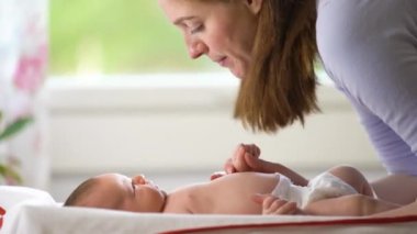 Annenin evde bebeğiyle oynaması, yeni doğanların ayaklarını öpmesi. Mutlu anne çocuk bakımı ve anneliğin tadını çıkarırken eğleniyor.