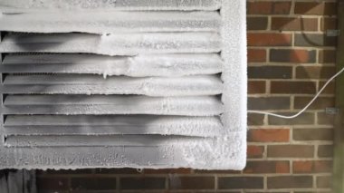 Finlandiya 'da soğuk bir kış gününde, kar ve buzla kaplı hava kaynağı ısı pompası ünitesi. Kuzey ülkelerinde kışın ev ısıtması