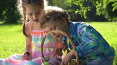 İki çocuk bahçede paskalya yumurtası avından sonra eğleniyor ve çikolatalı yumurta yiyor.