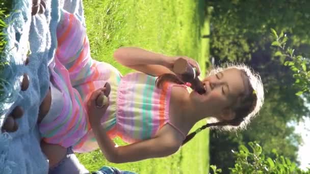 庭の裏庭でイースターエッグ狩りの後に楽しんでチョコレートの卵を食べる2人の子供と少女 — ストック動画