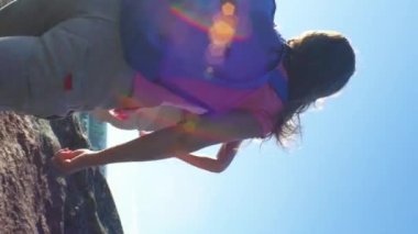 Sırt çantaları iki aktif genç kadınla cliff tırmanma vardır. Arkadaşlar yüksek rock tırmanmaya yardım. Nordic yatay, çam ağaçları, uçurumlar ve deniz.