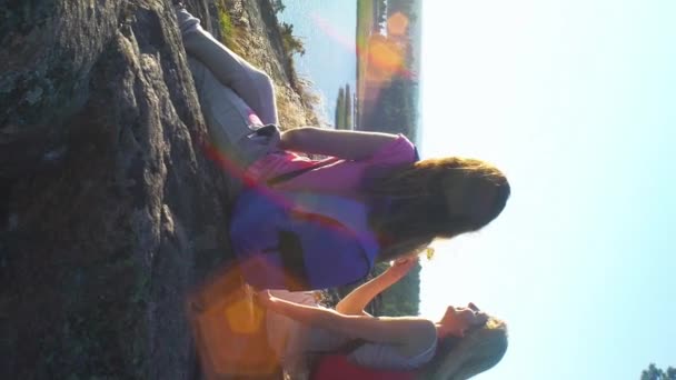 幸福的女性夫妇在一块高大的石头 在阳光下喝香槟 北欧景观与松树 悬崖和海 — 图库视频影像