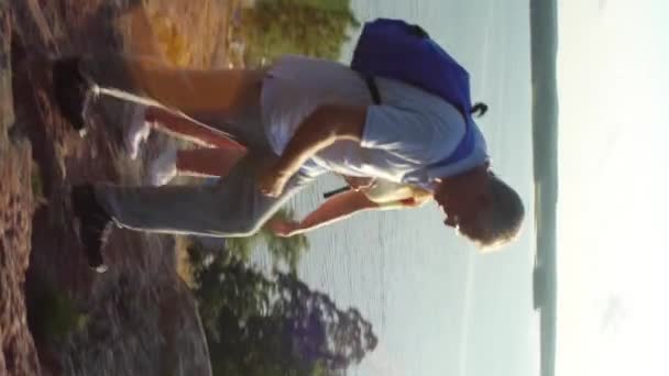 积极对老年夫妇在岩石上攀爬和欣赏日出 斯堪的纳维亚景观与海和松树 — 图库视频影像