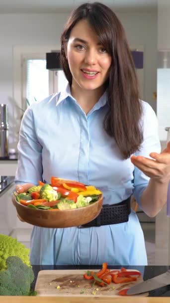 美しい若い女性ストリーミング放送ビデオブログおいしいと健康食品について自宅のキッチンで彼女のスマートフォンを使用して — ストック動画