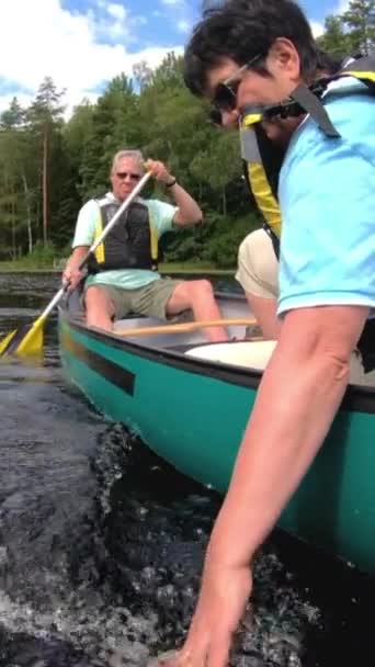 フィンランドの森林湖でカヌーをしているシニアカップル アクティブリタイヤは アウトドアスポーツを楽しんでいます 自然の中で楽しんでいる高齢者 垂直方向のビデオ — ストック動画