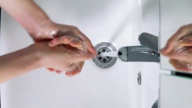 Genç adam evdeki banyoda ellerini yıkıyor, Coronavirus el yıkaması yapıyor temiz eller için. Üst görünüm
