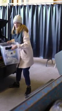 Genç bir kadın, atık, ev, inşaat atığı ve elektrik teçhizatı ayıklama ve geri dönüşüm merkezi olan HSY tasnif istasyonundaki bir çöp konteynerine eski eşyaları koyuyor.