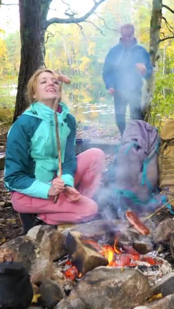 Młoda Kobieta Smaży Kiełbaski Otwartym Ogniu Lesie Mężczyzna Znajduje Pokazuje — Wideo stockowe